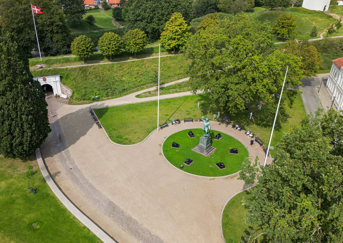 Luftfoto af Landsoldatpladsen i Fredericia med statue, kanoner og grønne områder.