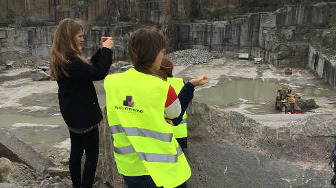 Besøg i stenbrud: Arbejdere og gæster ser på udvinding af sten.