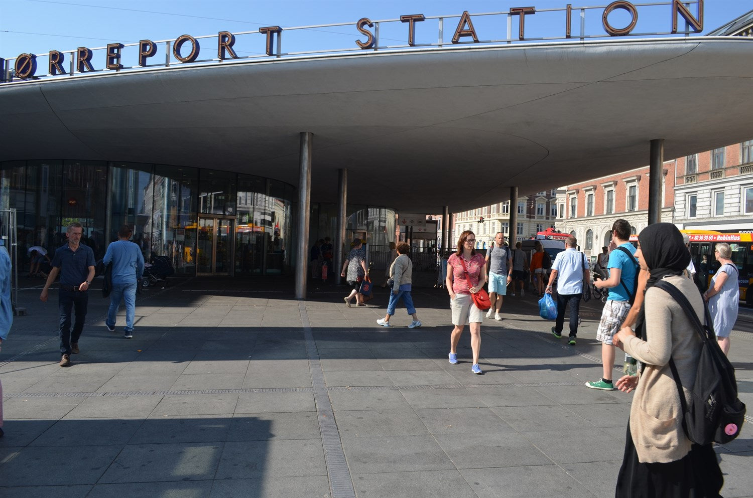 Nørreport Station i København. Mennesker går forbi stationsbygningen på en solskinsdag.