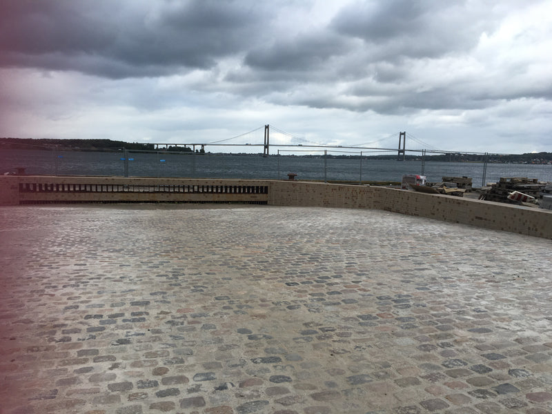 Klimatilpasningsprojekt: Ny belægning ved vandet med Storebæltsbroen i baggrunden.