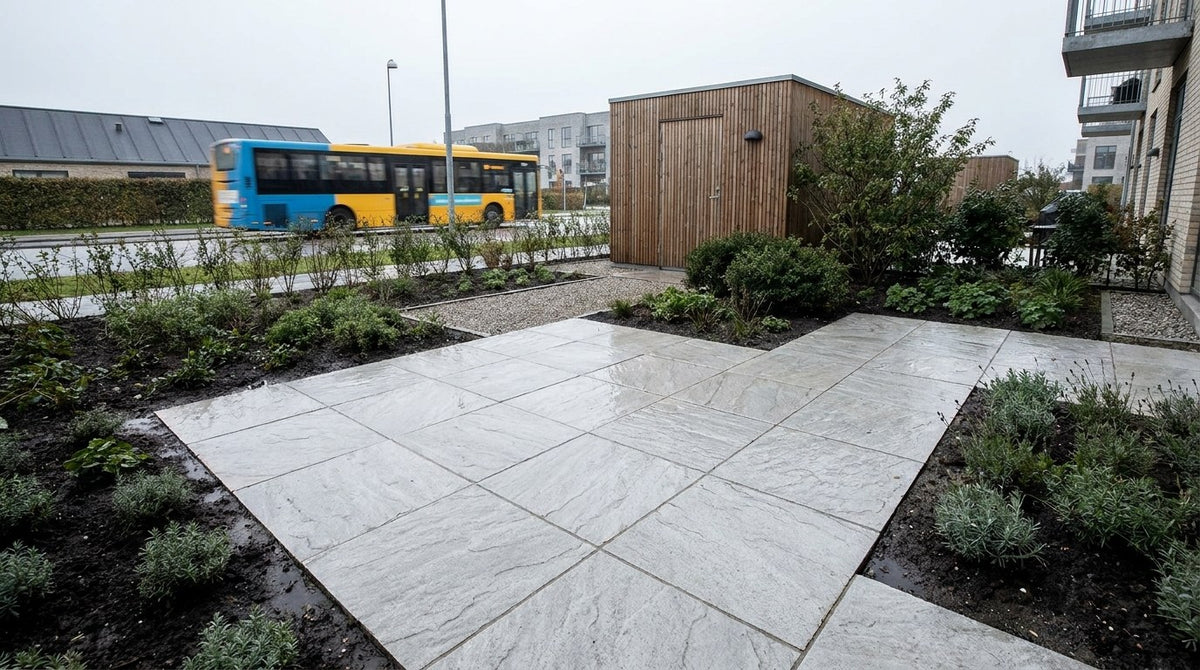 Store 90x90x8 og 30x90x10 naturstensfliser lagt i et stærkt trafikeret byrum med busgade