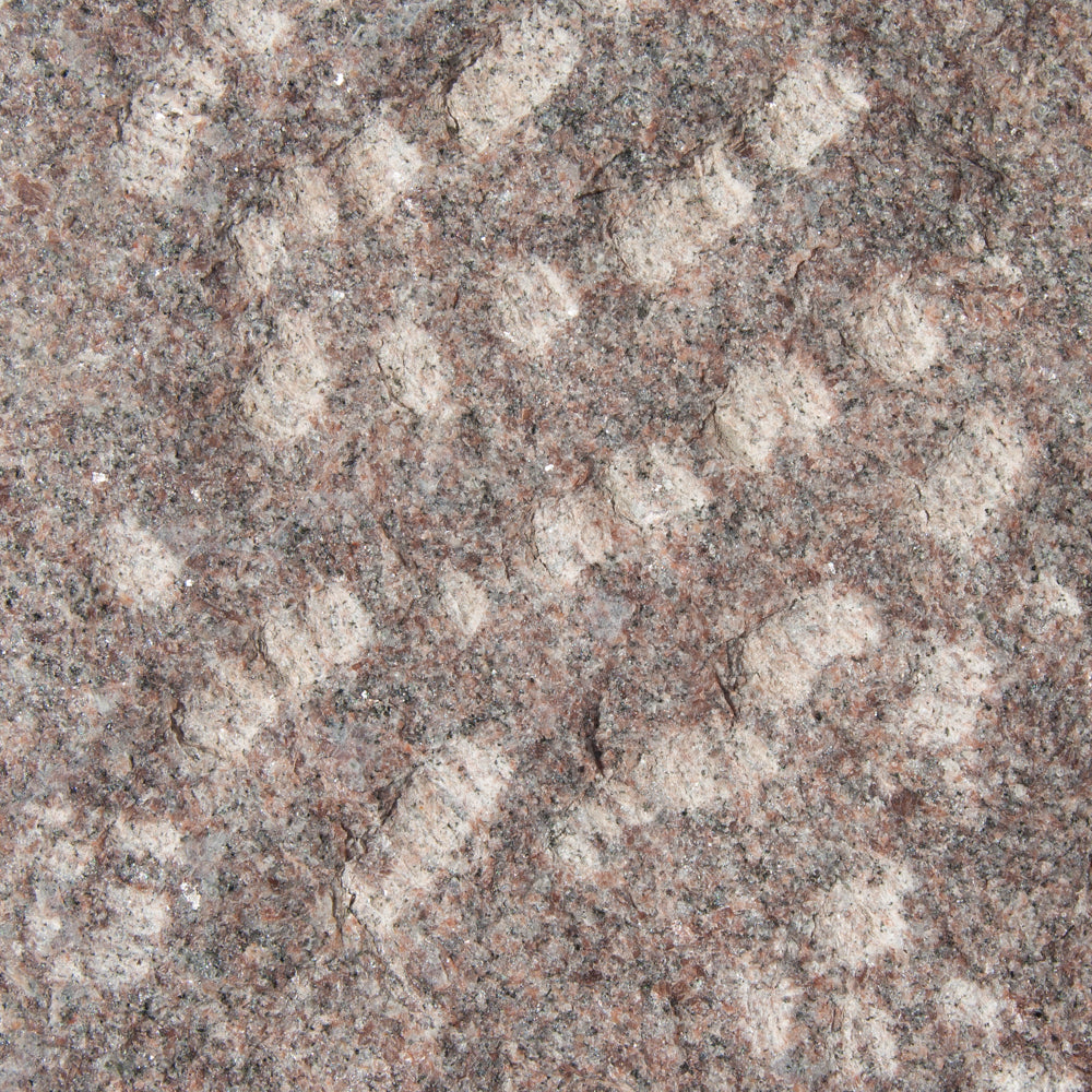 rødlig granitsten, kløvet overflade med lyse aftegninger.